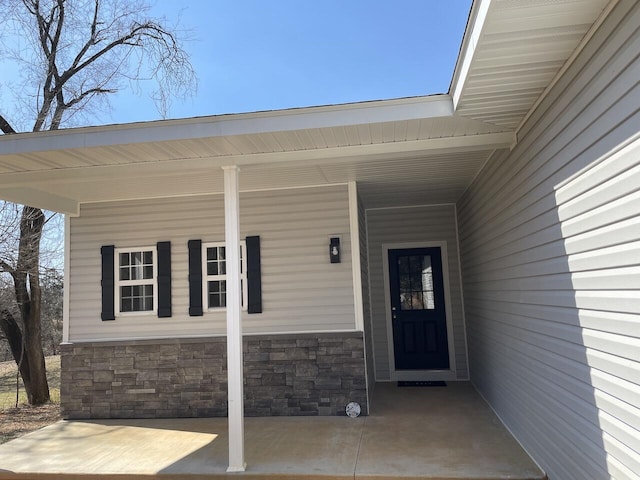 doorway to property with a carport and stone siding