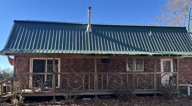 view of property exterior with metal roof, brick siding, and a deck