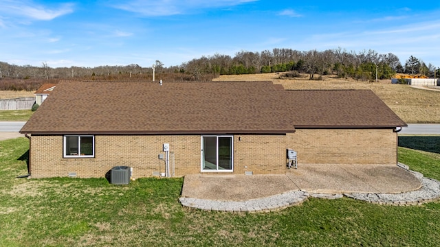 back of property with a yard, a patio area, roof with shingles, and crawl space