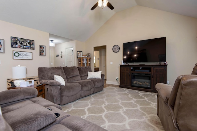 living area featuring a glass covered fireplace, a ceiling fan, and lofted ceiling