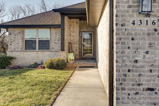 view of exterior entry featuring brick siding, stone siding, and a yard