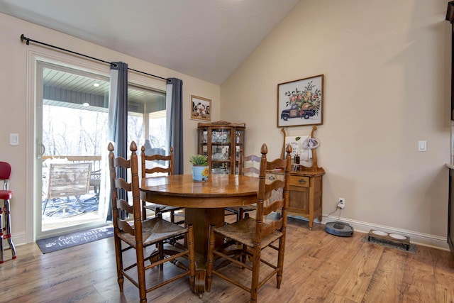 dining room with baseboards, lofted ceiling, and light wood-style flooring