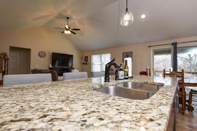 kitchen featuring light stone counters, wood finished floors, ceiling fan, a sink, and pendant lighting