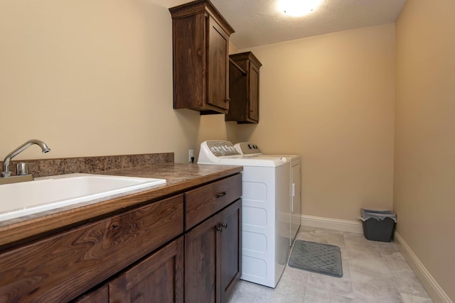 laundry area with a sink, baseboards, cabinet space, and independent washer and dryer