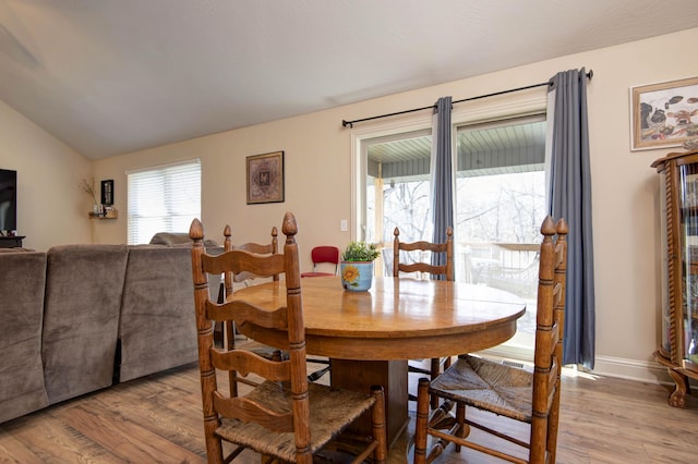 dining area featuring baseboards, lofted ceiling, and wood finished floors