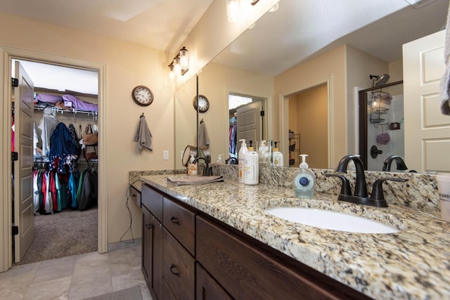 full bathroom with a sink, a walk in closet, double vanity, and a shower stall