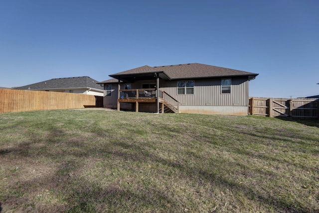 back of house with stairway, a gate, a fenced backyard, a deck, and a lawn