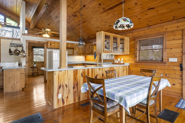 dining room with a ceiling fan, lofted ceiling with beams, wood-type flooring, wooden walls, and wood ceiling