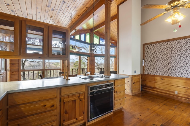 kitchen with oven, cooktop, a wainscoted wall, wood ceiling, and beam ceiling