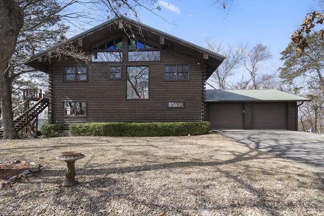 view of side of home featuring stairway, log siding, and a detached garage