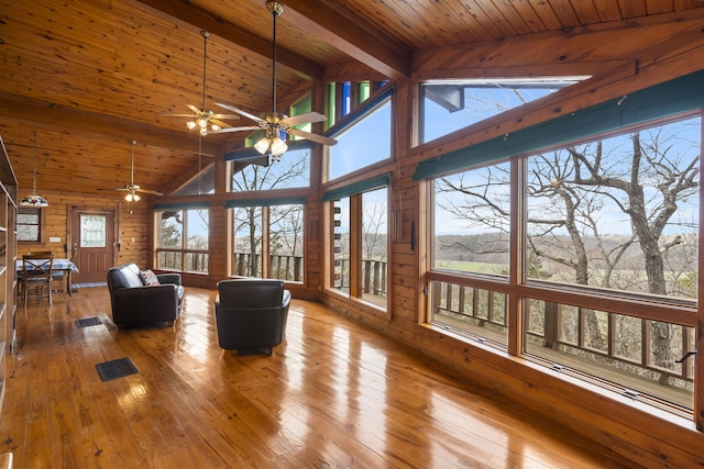 unfurnished living room with beam ceiling, wood-type flooring, wooden walls, and wood ceiling