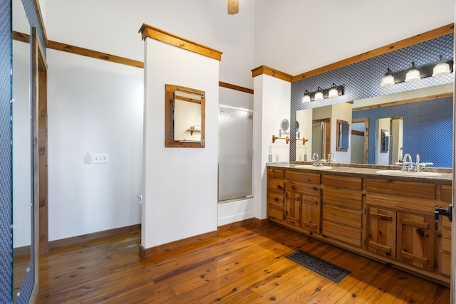 full bath featuring a sink, wood-type flooring, baseboards, and a shower with shower door