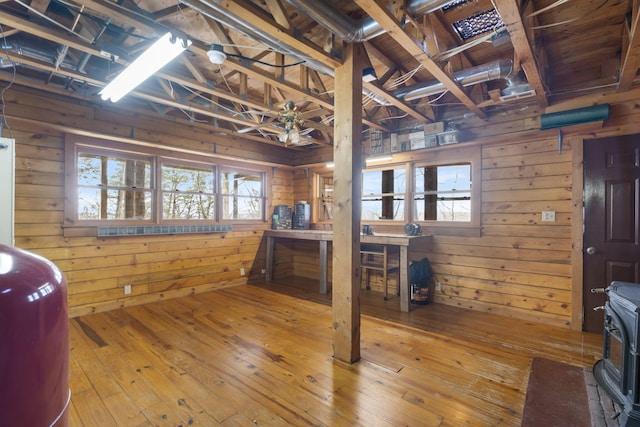 miscellaneous room featuring wood walls, a wood stove, and wood-type flooring