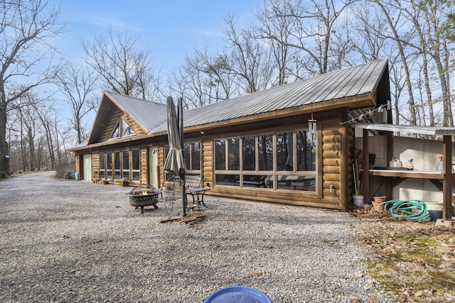 exterior space with metal roof, a sunroom, and an outdoor fire pit