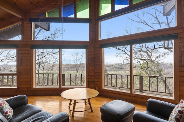 living area with high vaulted ceiling, wooden walls, and hardwood / wood-style flooring