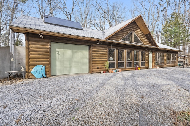 view of front of home with an attached garage, metal roof, and driveway