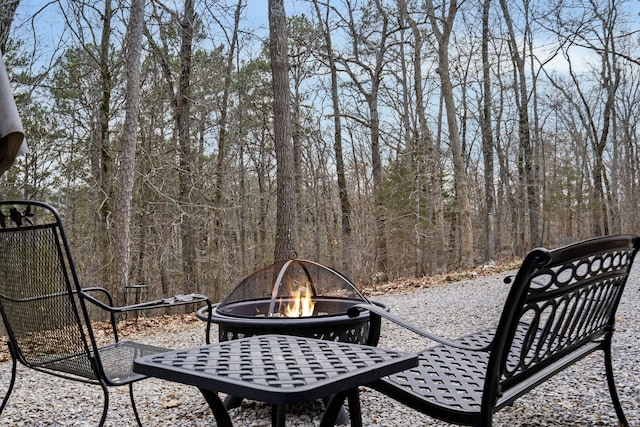 view of patio featuring a forest view and an outdoor fire pit