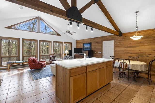 kitchen with light tile patterned flooring, wooden walls, open floor plan, and a sink