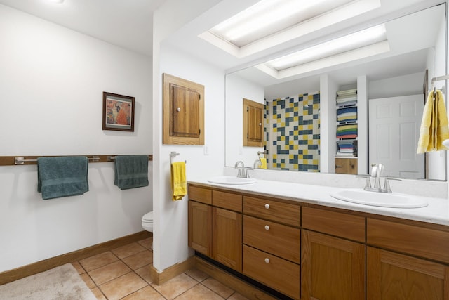 bathroom with tile patterned flooring, double vanity, toilet, and a sink