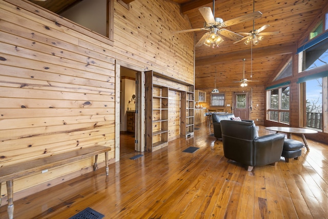 living room featuring high vaulted ceiling, a ceiling fan, hardwood / wood-style flooring, wooden walls, and wood ceiling