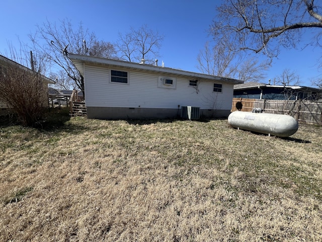 back of house featuring crawl space, a lawn, central AC unit, and fence