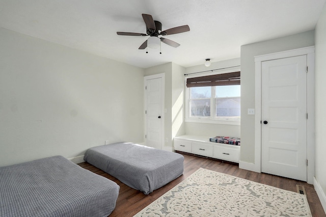 bedroom featuring dark wood-type flooring, a ceiling fan, and baseboards