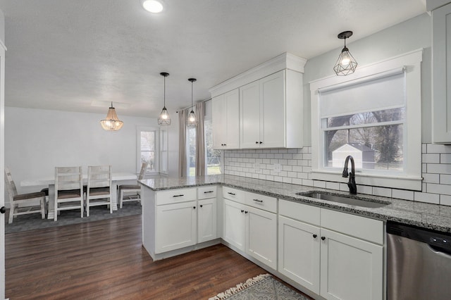 kitchen featuring a peninsula, a sink, dark wood-type flooring, white cabinets, and stainless steel dishwasher