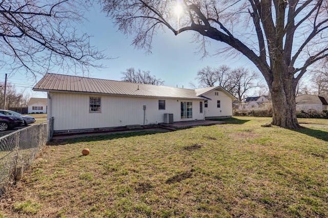 back of property with fence, central air condition unit, metal roof, a yard, and a patio