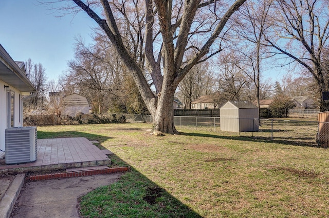 view of yard with an outbuilding, a fenced backyard, central AC, a storage unit, and a patio area