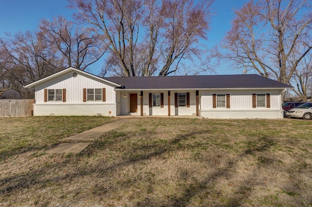 ranch-style house featuring a front lawn, fence, brick siding, and metal roof