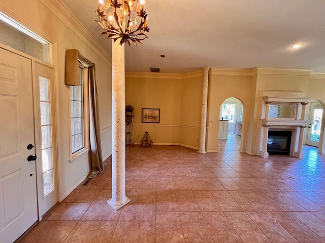 entrance foyer with visible vents, arched walkways, a glass covered fireplace, and crown molding