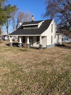 back of house featuring a lawn and a chimney