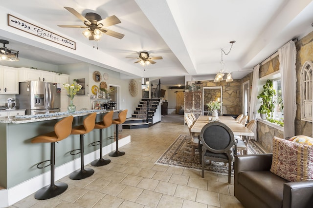 interior space featuring a breakfast bar area, light stone countertops, stainless steel fridge with ice dispenser, white cabinetry, and open floor plan