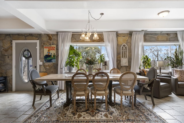 dining area featuring stone tile floors, a notable chandelier, and a wealth of natural light