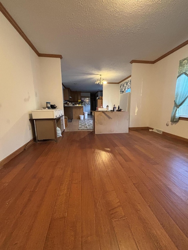 unfurnished living room featuring a textured ceiling, visible vents, dark wood-style flooring, and ornamental molding