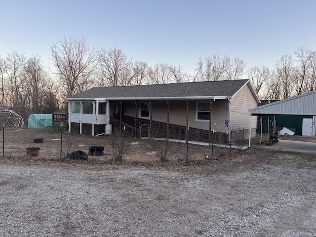 view of front facade featuring a shingled roof and fence