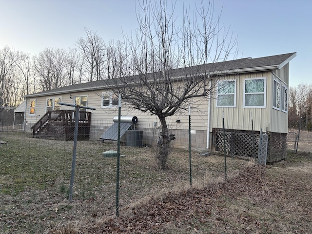 rear view of property featuring a shingled roof, cooling unit, board and batten siding, and a wooden deck