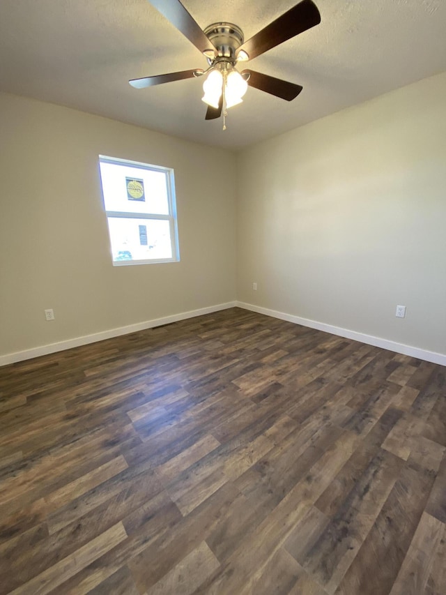 unfurnished room featuring dark wood finished floors, a ceiling fan, baseboards, and a textured ceiling