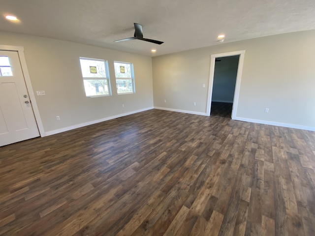 unfurnished living room with dark wood finished floors, plenty of natural light, ceiling fan, and baseboards