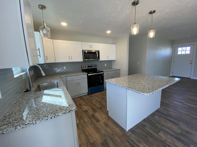 kitchen featuring stainless steel microwave, a center island, electric range oven, dark wood-style floors, and a sink