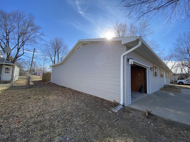 view of side of property with fence, a garage, and driveway