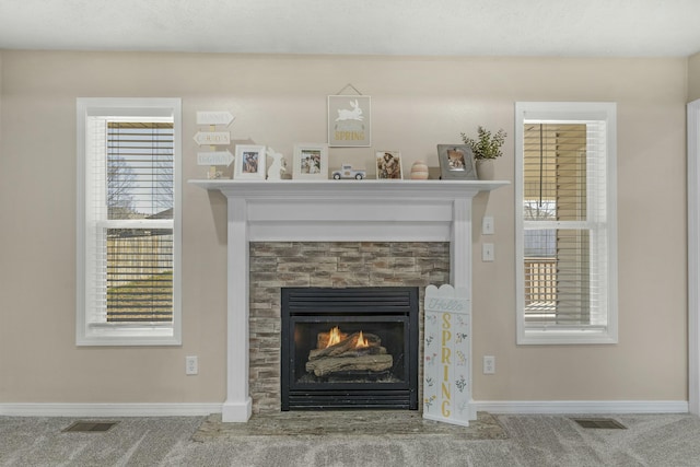 room details featuring visible vents, baseboards, and a lit fireplace