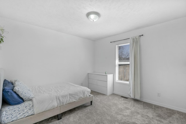 bedroom featuring baseboards, visible vents, carpet floors, and a textured ceiling