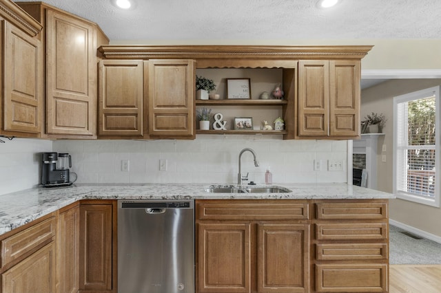 kitchen featuring visible vents, a sink, stainless steel dishwasher, tasteful backsplash, and light stone countertops