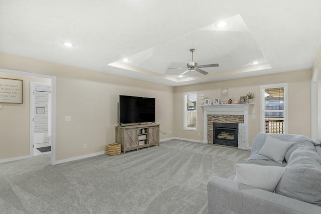 living room with baseboards, a tray ceiling, light carpet, and a healthy amount of sunlight