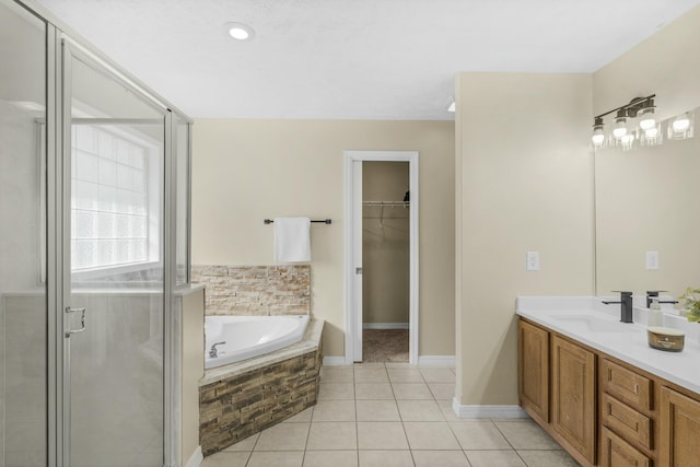 full bath featuring tile patterned flooring, a walk in closet, a stall shower, a bath, and vanity