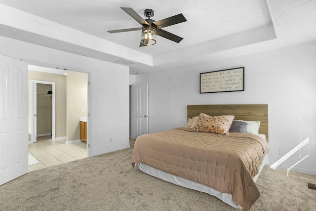 bedroom featuring a tray ceiling, baseboards, light colored carpet, and a textured ceiling