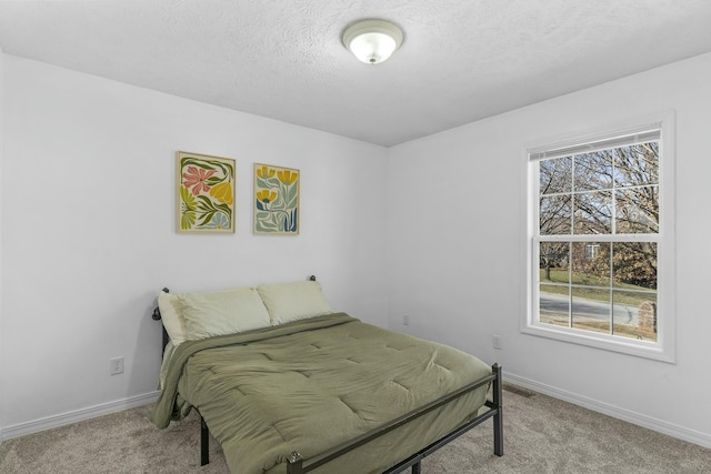 carpeted bedroom with baseboards, visible vents, and a textured ceiling