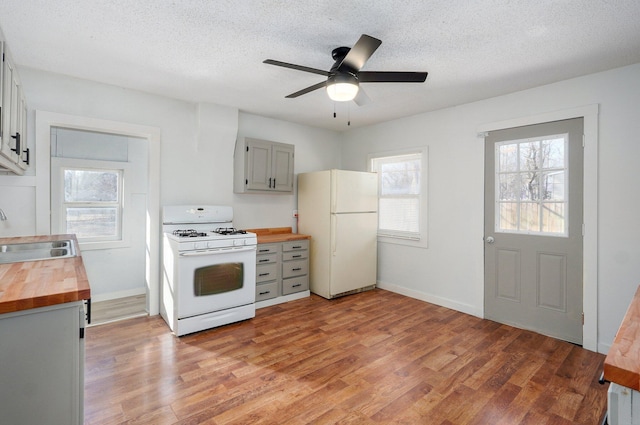 kitchen with wooden counters, gray cabinetry, light wood-type flooring, white appliances, and a sink