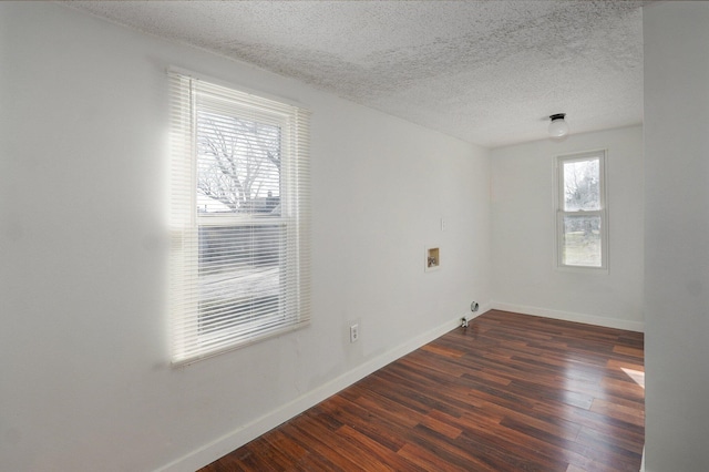 spare room with dark wood-type flooring, baseboards, and a textured ceiling